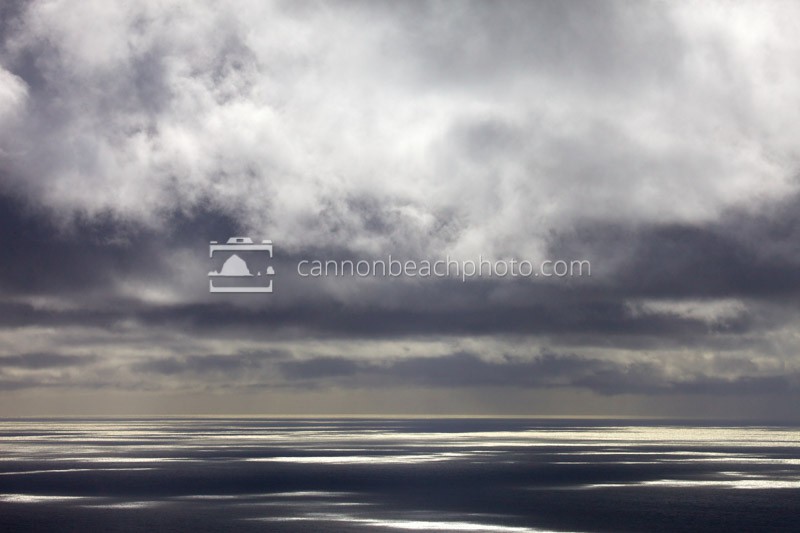 Patches of light glimmer on the Pacific Ocean as dramatic clouds roll above.