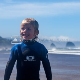 Kid in Wetsuit Grinning on the Beach